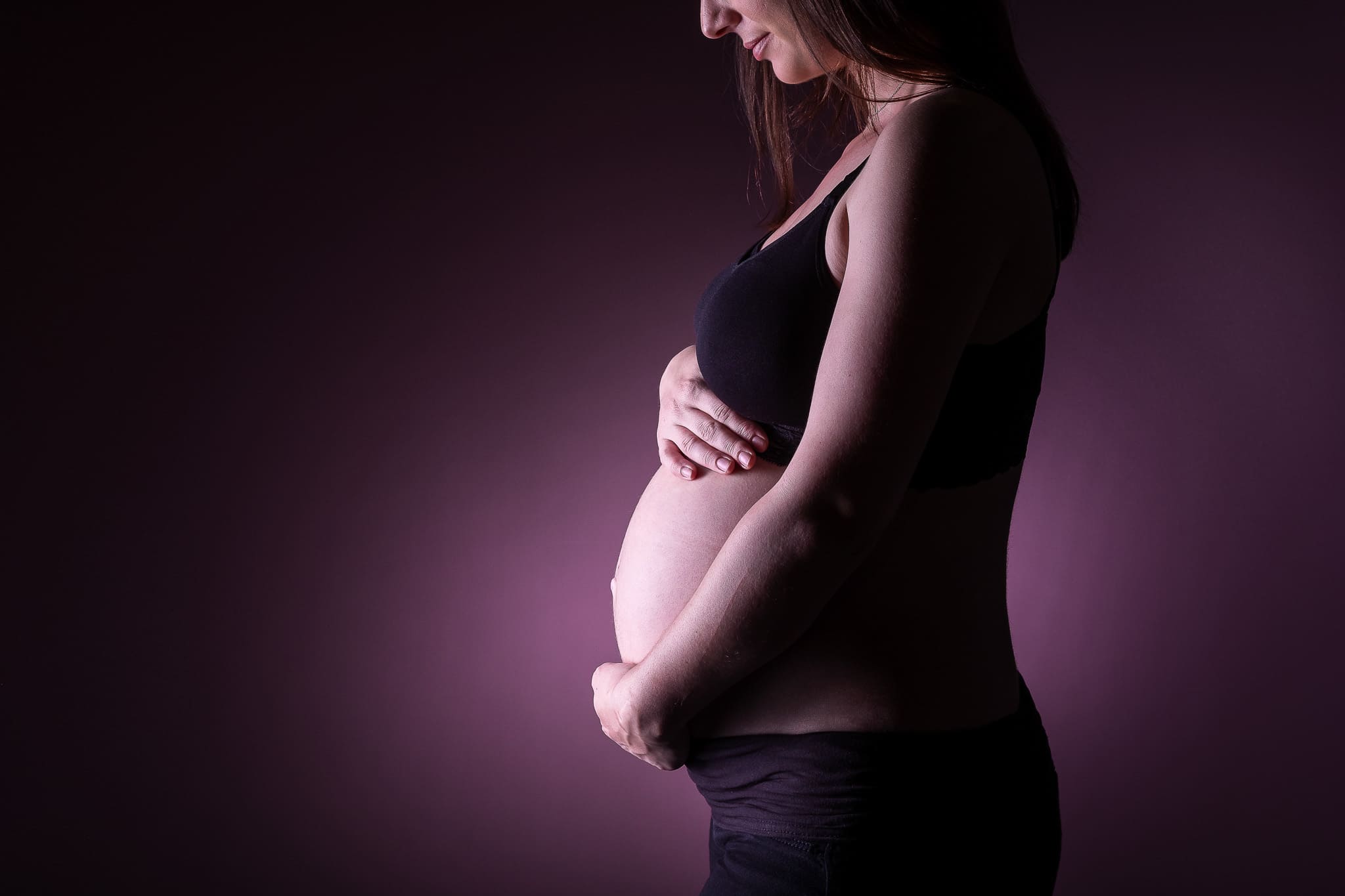 Photographe grossesse geneve - femme enceinte sur fond violet.